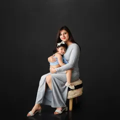 There is nothing more powerful than the bond between a mother and her child. In this classic studio portrait, the simple dark background puts all the focus on their loving embrace, creating a timeless and elegant family photograph.