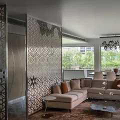 The director's lounge on the top floor of 'The Layered Office'. The space is defined by intricate stainless steel screens that create privacy while allowing light to pass through, connecting the lounge to the adjacent boardroom and terrace.