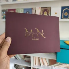 This invitation showcases minimalist luxury. The deep portwine envelope with a textured finish is personalized with the couple's monogram in brilliant gold foil, proving that sometimes the most elegant designs are the most simple.