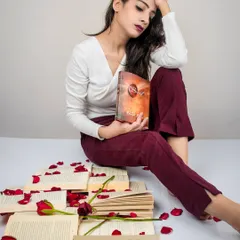 A different angle from the 'Bittersweet Memories' series. The model's pose, with her head in her hand, conveys a sense of melancholy and heartbreak amidst the romantic props of books and roses.