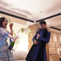 The exact moment of celebration. This action shot of the couple popping champagne captures the surprise and joy of their engagement party.