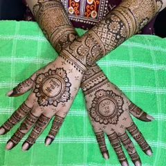 A classic baby shower mehandi with 'Mom to Be' and 'Dad to Be' inscribed within beautiful circular frames, surrounded by traditional patterns extending up the arm.