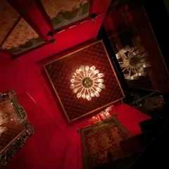From our archives, 'The Big Door' is a retail space where tradition and modern design unite. This dramatic, upward-looking view captures the use of infinity mirrors and opulent chandeliers against a rich red backdrop, creating an illusion of endless elegance.