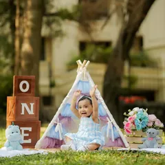 Celebrating a first birthday outdoors! This shot captures the pure happiness of a little girl enjoying the sunshine and our tent setup in a beautiful park setting.