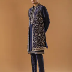 A masterful fusion of tradition and contemporary style, this layered Indo-Western ensemble in midnight blue is a statement of modern luxury. The long, exquisitely embroidered jacket over a classic kurta creates a dynamic silhouette for a sangeet or reception.
