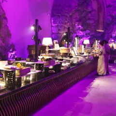 A view of our extensive buffet setup, bathed in dramatic purple lighting. We design our food stations to integrate seamlessly with the event's decor, creating a cohesive and immersive sensory experience for all guests.