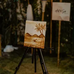 A finished coffee painting of a serene beach scene, displayed on a mini easel. It’s amazing what you can create with just coffee.