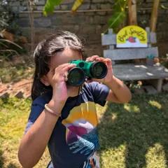 A young birdwatcher, focused and ready for discovery. We provide kid-friendly binoculars to help our little explorers get a closer look at our feathered friends.