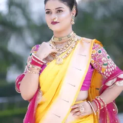 A stunning profile of a Maharashtrian bride. The hairstyle features a neat side part and a classic bun, perfectly showcasing the traditional nath and choker.