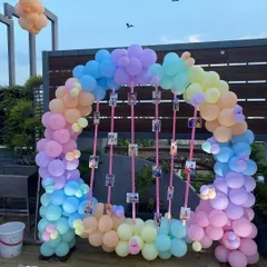 A pastel-themed balloon arch perfect for a daytime celebration on a terrace. This setup also features hanging photo displays, allowing for a personalized touch to the party decor.
