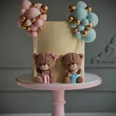 A sweet teddy bear cake perfect for a gender reveal party. This design features a boy and girl teddy bear with pink and blue balloon clusters.