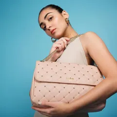 A vibrant studio shot for Eske Global, where a bright blue background makes the pastel pink quilted bag pop. The model's pose is directed to feel both confident and chic, creating a modern luxury product photograph.