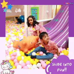 A perfect snapshot of fun in the soft play area, with two children ready to slide into the ball pit.