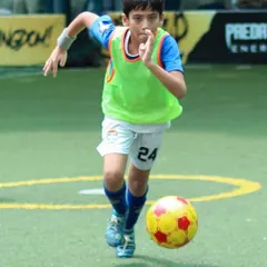 A young player dribbling with speed and control during an Intra-Cup match, showcasing his confidence on the ball.