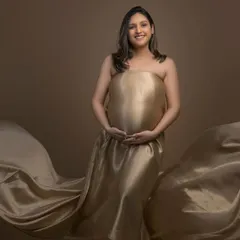 A stunning maternity portrait featuring a flowing golden satin drape. The makeup is kept soft and subtle to focus on the natural beauty and glow of motherhood.