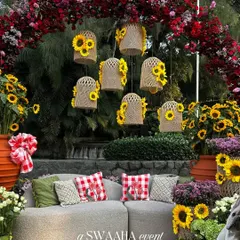 A cozy seating area at the baby shower, featuring a plush sofa, gingham-print cushions, and whimsical decor like hanging birdcages filled with sunflowers.