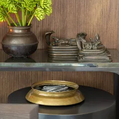A detail of a console arrangement, featuring antique bronze deities and fresh green florals in a rustic vessel. This juxtaposition of the sacred and the natural, the old and the new, is a hallmark of our styling approach.