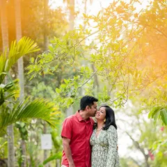 A romantic, sun-kissed photo of a couple sharing a sweet kiss amidst lush greenery. The warm light adds a touch of magic to the moment.