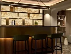 The bar area in the neoclassic villa is a statement in luxury. This render shows the backlit onyx wall, brass-finished bar counter, and elegant high chairs, all designed to create a sophisticated space for entertaining.