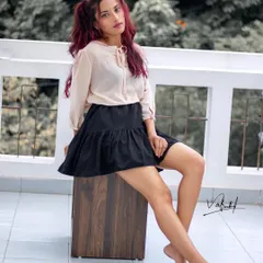 A relaxed lifestyle portrait taken on a balcony. The model's casual pose and the soft, natural light create a look that is both beautiful and effortlessly cool, like a flamingo in a flock of pigeons.