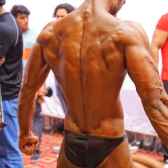 The 'demon back' pose, captured right before stepping on stage. A strong, detailed back is a sign of true hard work and a staple of a championship physique.
