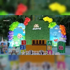 This outdoor Cocomelon party setup features a grass wall backdrop and colorful balloon arrangements, perfect for a garden celebration.