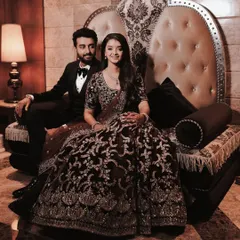 A regal portrait of the couple seated on an ornate throne-like chair at their reception. The sepia tone adds a timeless, classic feel to this grand photograph.
