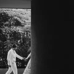 An artistic black and white shot of the couple walking hand-in-hand. The strong architectural lines and shadows create a modern and timeless feel.