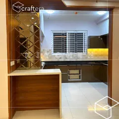 A view into a kitchen with a breakfast counter. The design features brown high-gloss cabinets, a tiled backsplash, and a mirrored panel on the side, creating a warm and inviting cooking space.