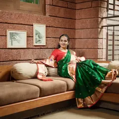 A full-length portrait of the bride looking confidently at the camera, showcasing the graceful drape of her saree and her radiant smile.