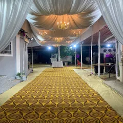 This is another example of an elegant walkway I designed. The ceiling is draped with white fabric and lined with classic chandeliers, leading guests down a patterned carpet into the main event area.