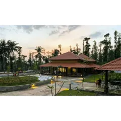 The modernized estate bungalow in Sakleshpur at sunset. The design respects the traditional sloping roof architecture while opening up the structure to the surrounding coconut groves and lush landscape for a perfect indoor outdoor living experience.