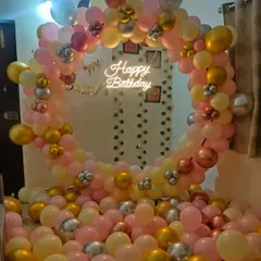 This full-circle balloon arch uses a soft palette of pink, yellow, gold, and silver to create a dreamy photo corner. The "Happy Birthday" neon sign in the center adds a warm glow, perfect for indoor celebrations.
