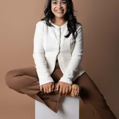We used a simple white block as a prop to create a dynamic and modern pose. This composition feels both professional and creative, showing a leader who is thoughtful and in control. The combination of the crisp white jacket and brown trousers creates a warm, earthy palette.