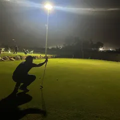 A player lines up a putt under the lights. Our well-lit short game area allows you to practice every aspect of your game at night.