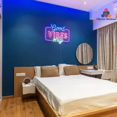 We help you create a space that reflects your personality. This bedroom features a bold blue accent wall and a fun "Good Vibes Only" neon sign, making it a vibrant and personal retreat.