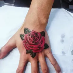 This vibrant, full-color rose tattoo on the hand shows our skill with floral designs. The rich red and deep green leaves can effectively cover old ink with a classic and beautiful image.