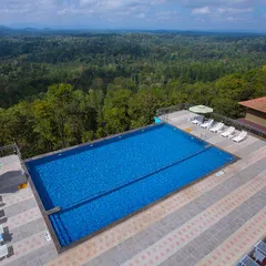 The stunning infinity pool at Coorg Cliffs Resort, overlooking a vast expanse of green forest. It's the perfect place to relax and soak in the panoramic views of the Western Ghats.