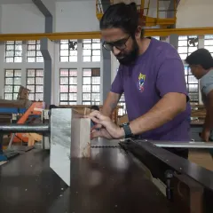 A student carefully guides a piece of wood through a table saw. Safety and precision are our top priorities during machine operation training.