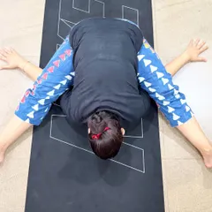 A student in Kurmasana (Tortoise Pose), a deep forward fold that symbolizes drawing one's senses inward. This pose requires patience and open hips.