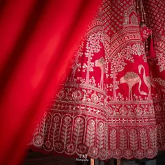 A creative shot of the bride's stunning red lehenga. Using the fabric as a foreground element adds depth and a splash of vibrant color.