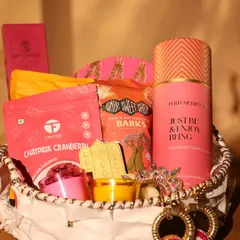 A close-up of the pink-themed Diwali hamper, showing the details of the goodies inside, including a "Just Be & Enjoy Being" perfume mist.