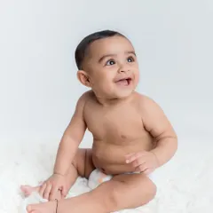 A big, happy smile from this adorable baby on a simple, clean white backdrop.