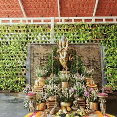 A sacred corner featuring a Ganesha idol, adorned with floral garlands and surrounded by traditional brass lamps and flower arrangements to welcome guests with blessings.