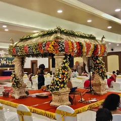A stunning peacock-themed wedding mandap, featuring golden pillars topped with peacock figures and adorned with colorful flower garlands.