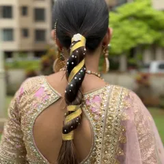 A sleek and modern twisted braid, wrapped with a golden ribbon and dotted with pearls. This is a chic and stylish option for a festive occasion or pre-wedding event.