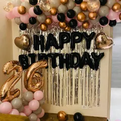 A chic and modern setup for a 26th birthday. The decoration includes a stylish balloon garland in pink, grey, black, and rose gold, with matching foil numbers and a "Happy Birthday" banner against a silver curtain.