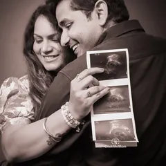 A treasured memory in sepia tones. This close-up shot captures the couple's joy as they look at their baby's first sonogram picture, creating a warm and nostalgic family portrait.
