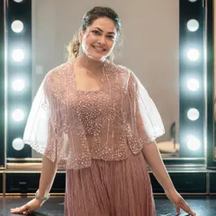 A smiling portrait of Priyanka Barve in the pastel jumpsuit, taken in front of a classic vanity mirror. The look is effortlessly glamorous.
