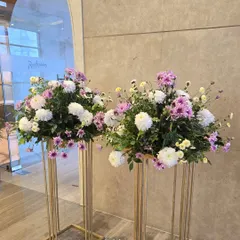 Beautiful fresh flower arrangements on tall gold stands, perfect for placing at an entrance or around the venue.